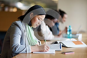 Student, library and studying with book at desk for university or education for future, exam or scholarship. Asian