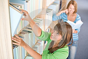 Student in library - two happy woman choose book