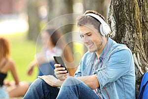 Student listening music with headphones in a park