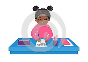 Cute African girl writes on the paper at the desk. photo