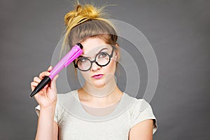 Woman holding big oversized pencil thinking about something