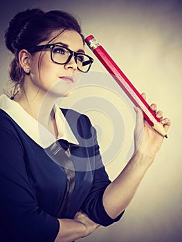 Woman holding big oversized pencil thinking about something