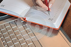 Student making notes on the table with a laptop