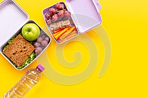 Student meal in purple lunch boxes filled with sandwich and fruits