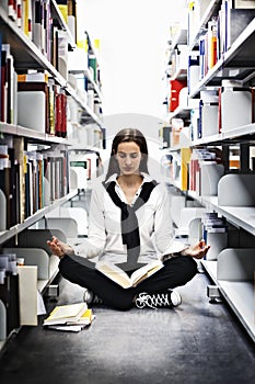 Student meditating over a book in library.