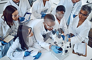 Student, microscope and science in university class, group and learning with woman lecturer, education or study