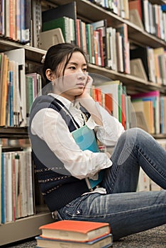 Student next to bookshelf looking depressed