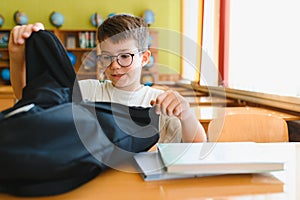 Student opening backpack at school desk getting ready for class