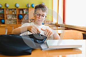 Student opening backpack at school desk getting ready for class