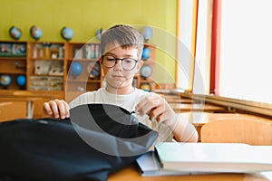 Student opening backpack at school desk getting ready for class