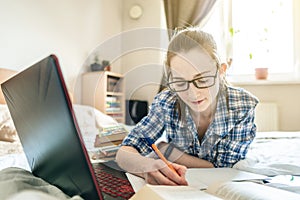 Student is passing online lesson on the Internet at home lying on a bed. Remote learning in schools and universities