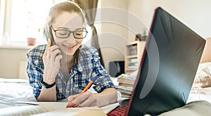 Student is passing online lesson on the Internet at home lying on a bed. Remote learning in schools and universities