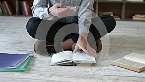 Student with phone making cheat sheet in library
