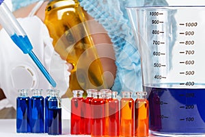 Student with pipette, protective clothing, glasses in a chemistry lab