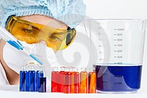 Student with pipette, protective clothing, glasses in a chemistry lab