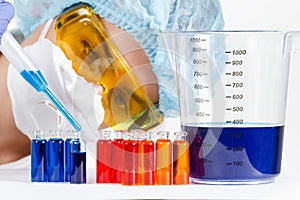 Student with pipette, protective clothing, glasses in a chemistry lab