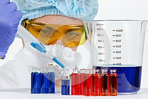 Student with pipette, protective clothing, glasses in a chemistry lab