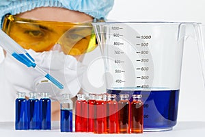 Student with pipette, protective clothing, glasses in a chemistry lab