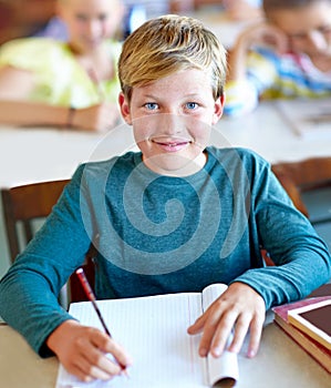 Student, portrait and boy writing notes for learning in classroom, book and problem solving at school. Male person