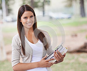 Student, portrait and happy on campus in park, technology and education with books for studying. University, smile or