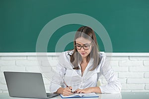 Student preparing exam and learning lessons in school classroom. Female freelancer or a student with laptop computer.