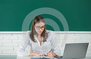 Student preparing exam and learning lessons in school classroom. Female freelancer or a student with laptop computer.