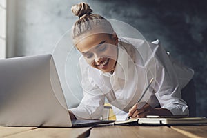 Student preparing for seminar, writing notes in copybook, searching for information online. Female working