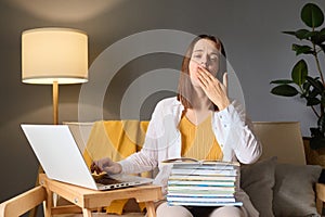 Student preparing for a test. Laptop in the study room. Sleepy young woman student working at home sitting