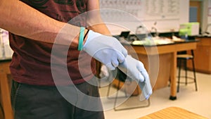 Student putting on medical rubber gloves in science laboratory