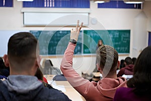 The student raises his hands asking a question in class in college