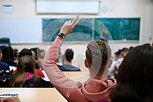 The student raises his hands asking a question in class in college