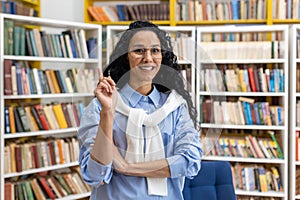 Student raising hand in library full of books