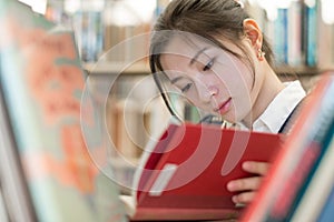 Student reading a book on bookshelf