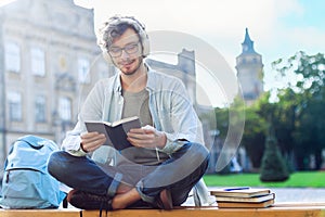 Student is reading book outdoor at campus.