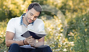Student reading book in a park