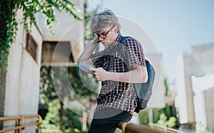 Student reading notes in school courtyard during sunny day