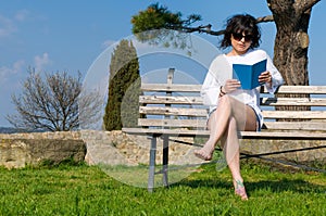 Student reads the book sitting on a bench