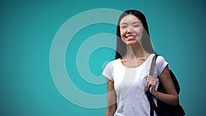 Student with rucksack smiling and looking at camera, blue background, statistic