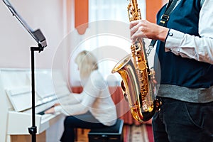Student saxophone at a lesson in a music school close-up on background of a teacher at the piano