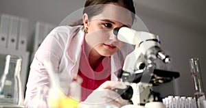 Student scientist looks through microscope in research laboratory