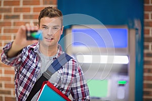 Student showing his card to camera at the atm