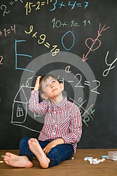 The student sits on the background of the school board in thoughtfulness over the solution of the problem