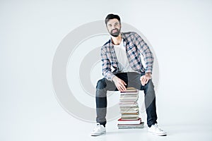 Student sitting on pile of books on white with copy space