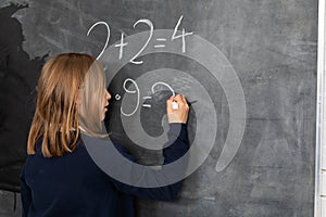 The student solves a math problem standing at the blackboard in her classroom