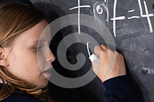 The student solves a math problem standing at the blackboard in her classroom