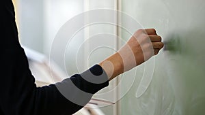 Student standing at the blackboard writing with chalk