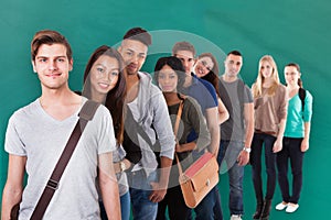 Student Standing In Row Against Green Background