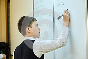 A student stands at the blackboard and writes a task.
