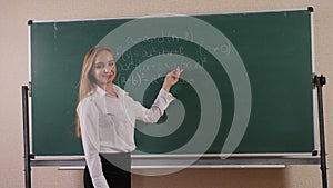 A student stands near the blackboard on which mathematical formulas are written.