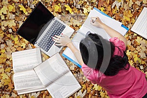 Student studying on the autumn leaves